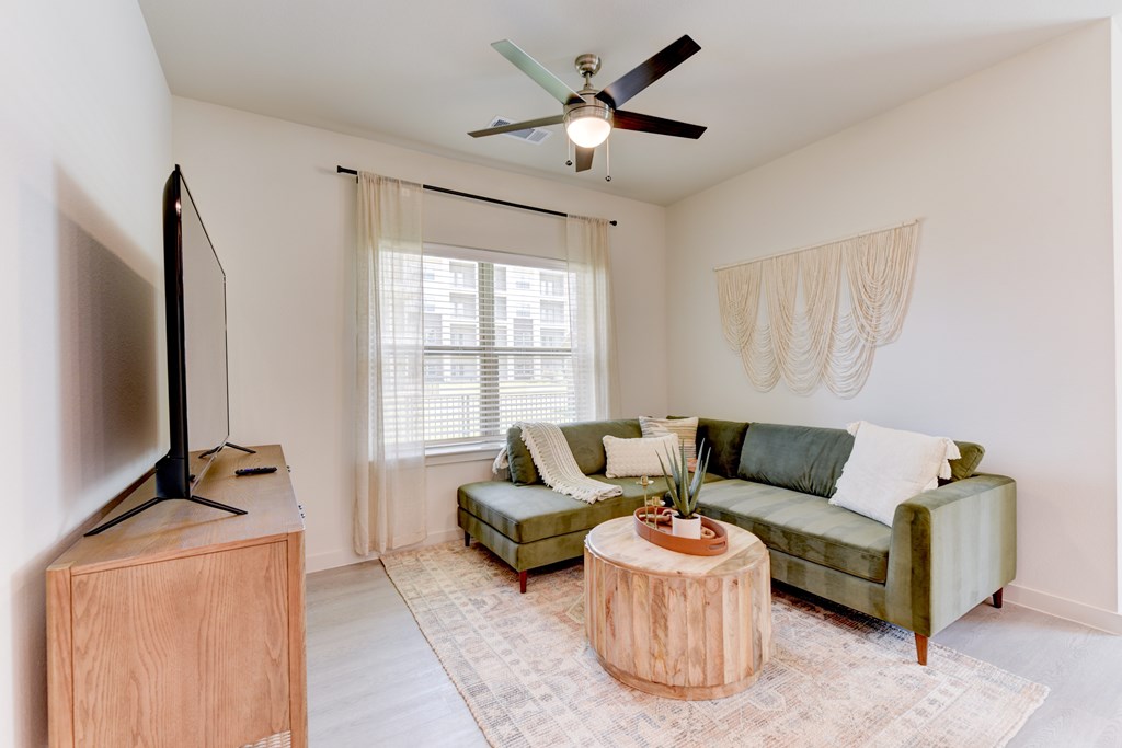 A living room with a green couch, a wooden table, and a television.