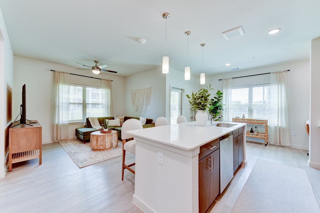 A spacious kitchen and living room with white walls and wooden floors.
