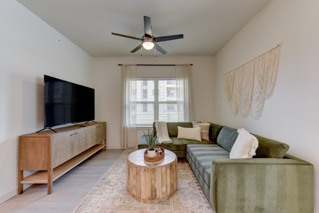 A living room with a green couch, a wooden table, and a flat screen TV.