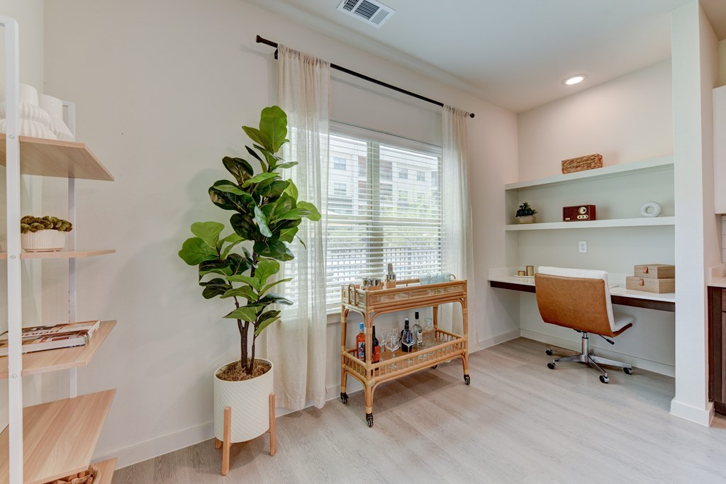 A room with a desk, chair, and a potted plant.