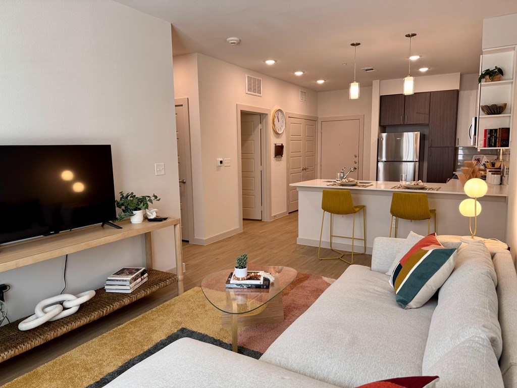 A modern living room with a white couch and a television on a wooden stand.