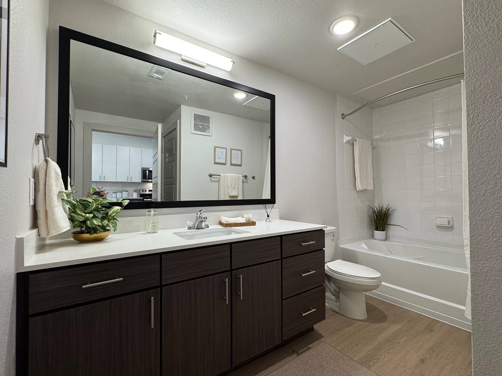 A bathroom with a large mirror, a white sink, and a white toilet.
