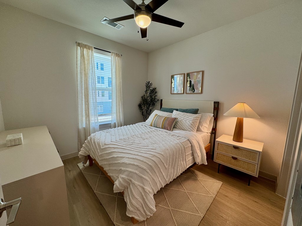 A bedroom with a bed, nightstand, and a ceiling fan.