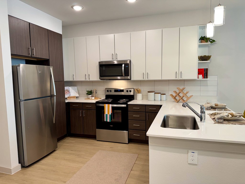 A modern kitchen with a stainless steel refrigerator, microwave, oven, and sink.