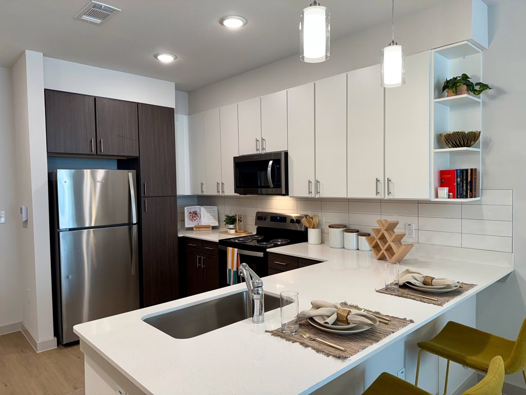 A modern kitchen with a white countertop and a stainless steel refrigerator.