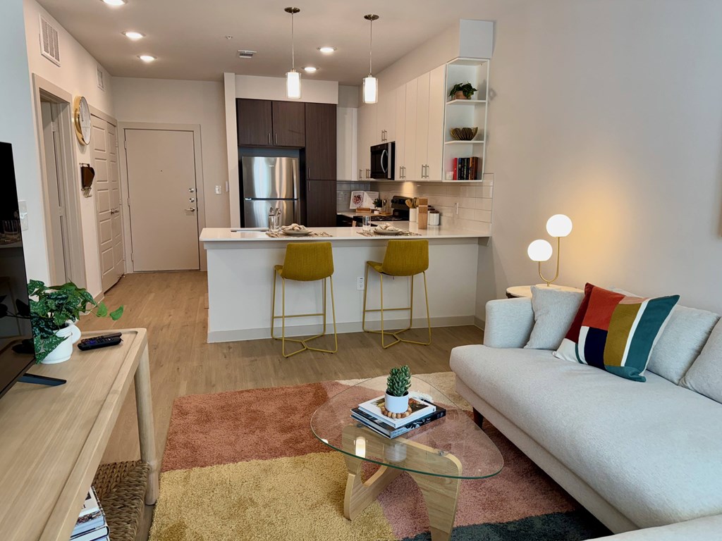 A modern living room with a white sofa, yellow chairs, and a glass coffee table.