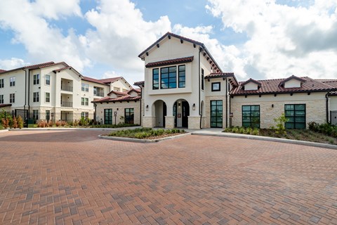 A large building with a red brick courtyard in front.
