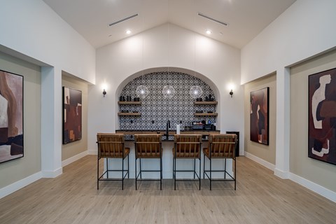A modern kitchen with a bar area and chairs.