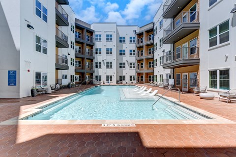 A swimming pool in the middle of a courtyard surrounded by buildings. at Park South Apartments, Texas