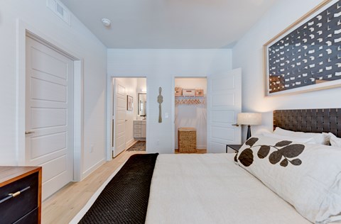 A bedroom with a large bed and a painting on the wall. at Park South Apartments, Austin, TX