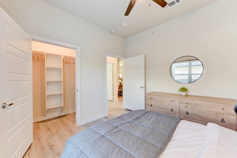 A bedroom with a bed, dresser, and a mirror on the wall. at Bridge at Speyside Apartments, Austin, Texas