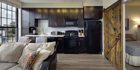 A kitchen with a black refrigerator and wooden floors.