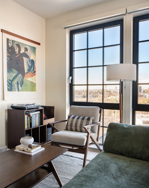 A living room with a chair, a table, a book and a painting.