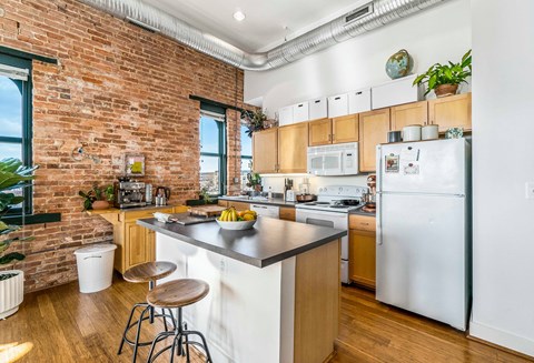 A kitchen with a brick wall and wooden cabinets.