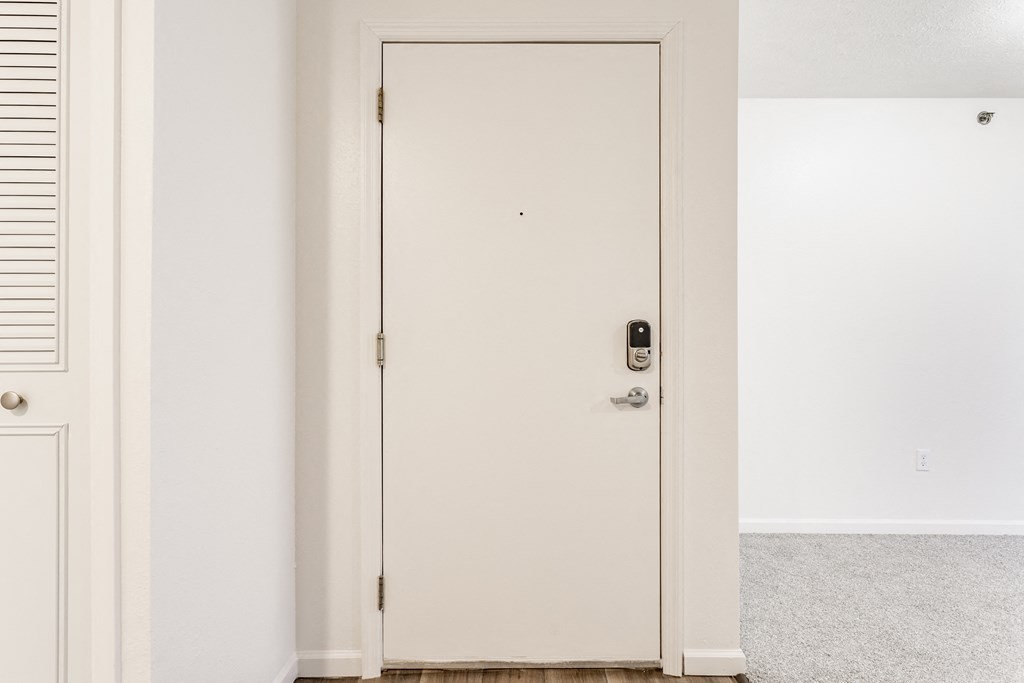A white door with a black handle and a lock at Huntington Cove Apartments, Merrillville, IN, 46410