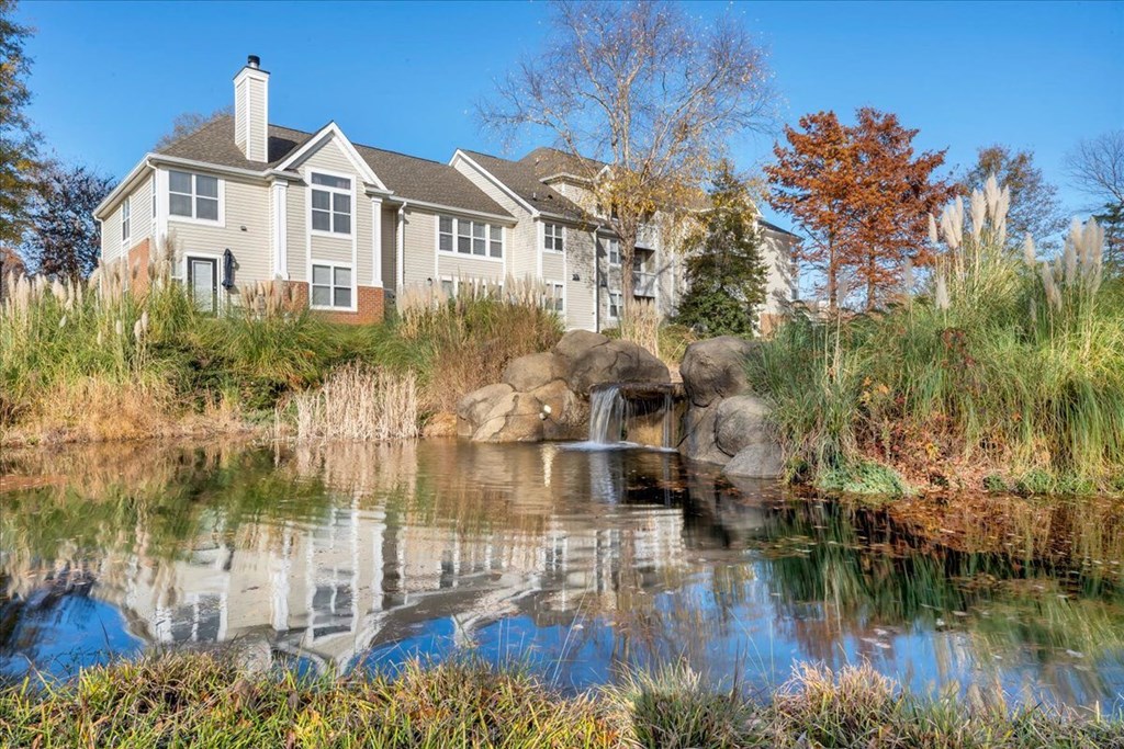 a small waterfall in a pond in front of a house