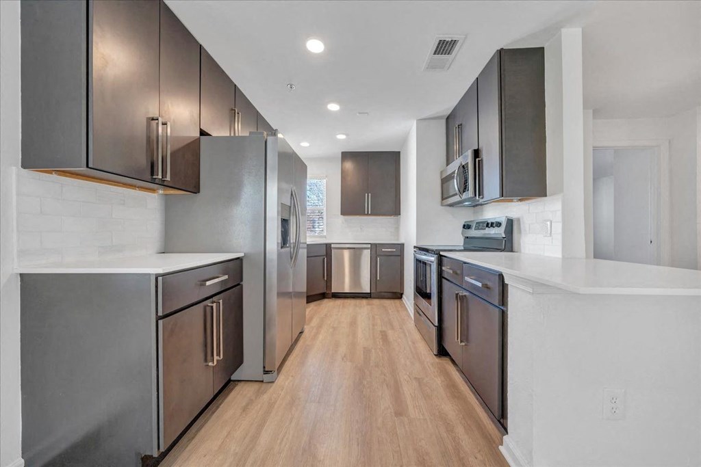 a large kitchen with stainless steel appliances and white counter tops at The Vinings Apartments, Richmond, Virginia