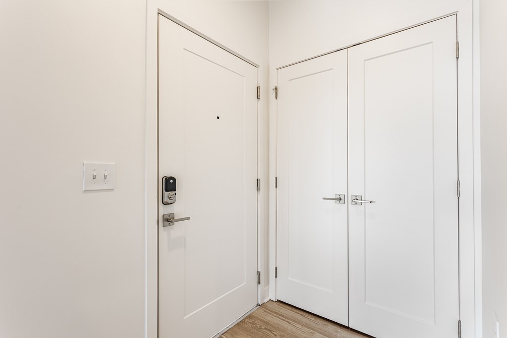 A white door with a keypad lock is open to a hallway with three white doors at Upper Vue Flats, Dublin