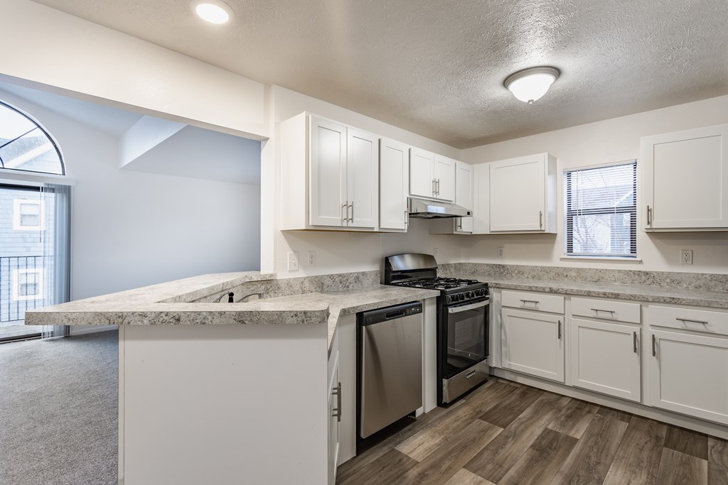 A kitchen with white cabinets and a marble countertop.