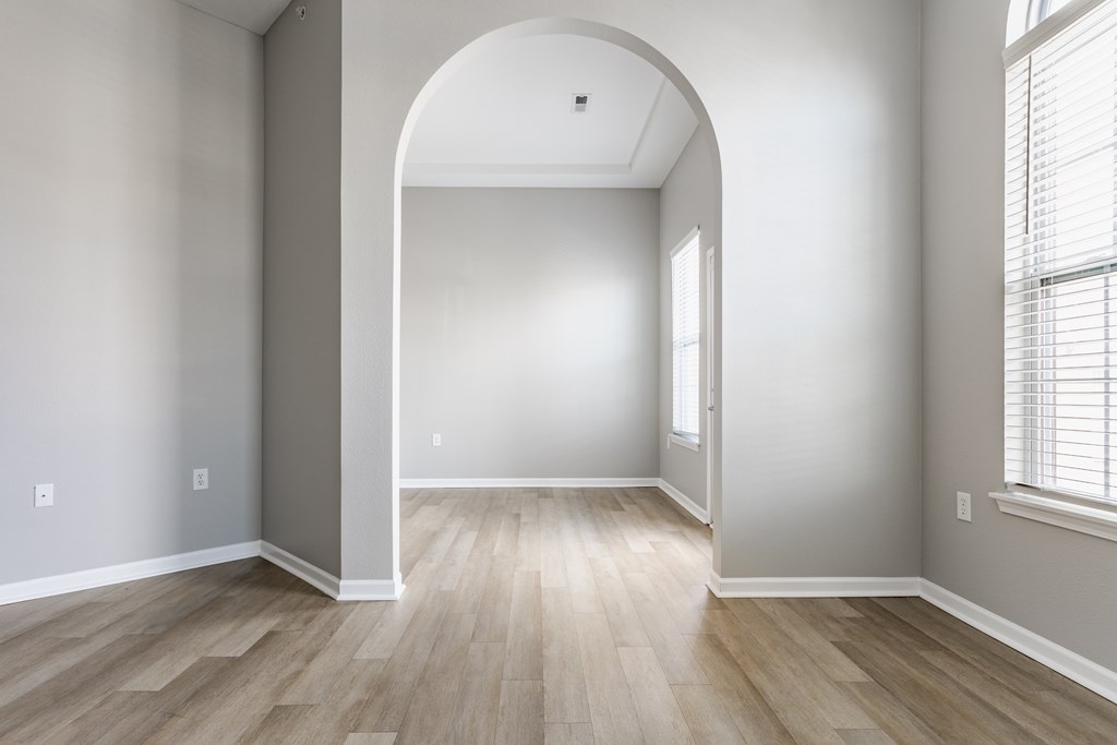 A room with a large arched doorway and wooden flooring.