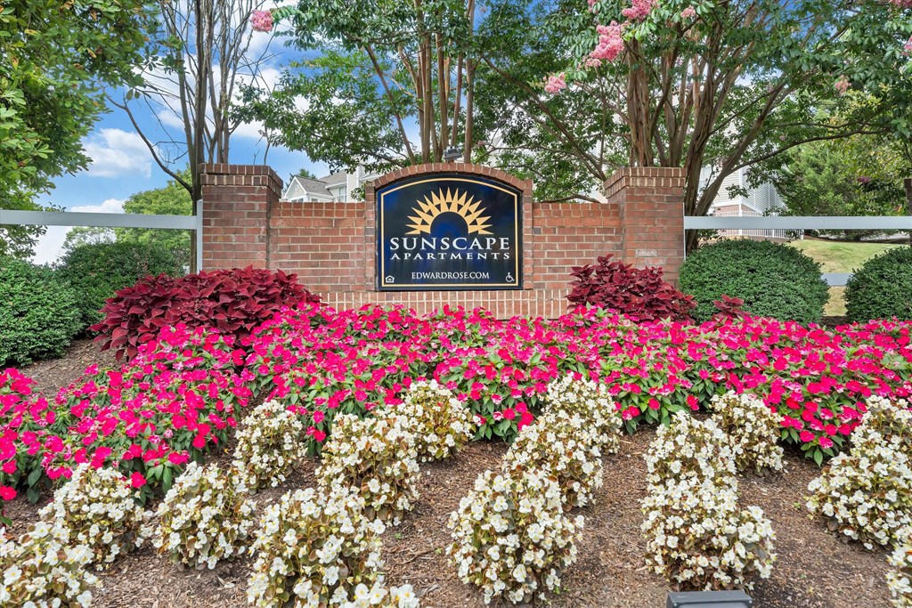 a sign and flowers in front of a brick wall at Sunscape Apartments, Roanoke, VA