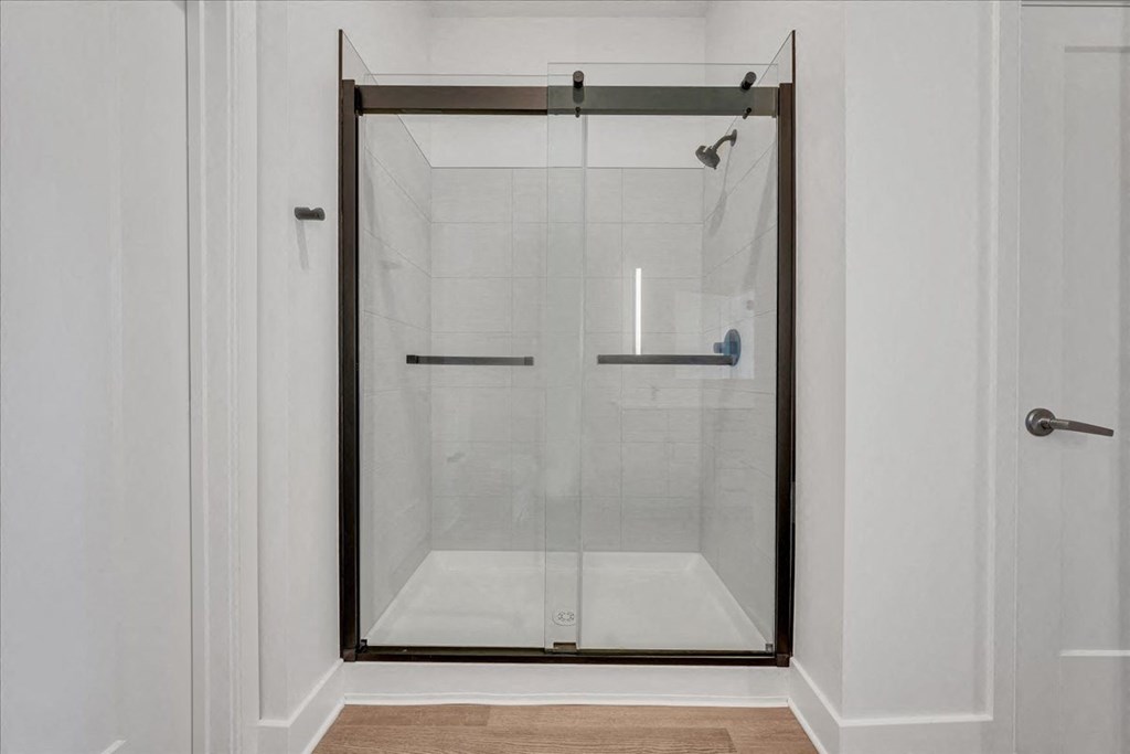 a shower with a glass door in a white bathroom at Luxe 360 in Midlothian, Virginia