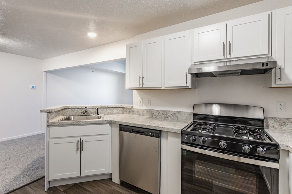 A kitchen with white cabinets and a stainless steel dishwasher and oven at Huntington Cove Apartments, Merrillville, IN, 46410