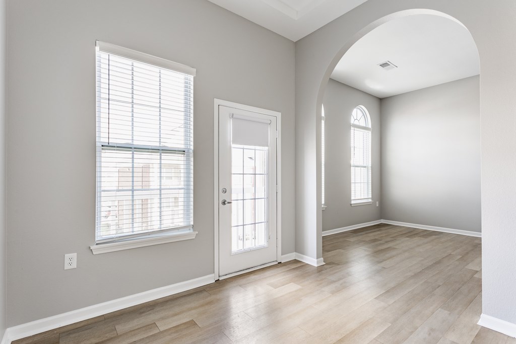 A room with a white door, a window with blinds, and a wall socket.