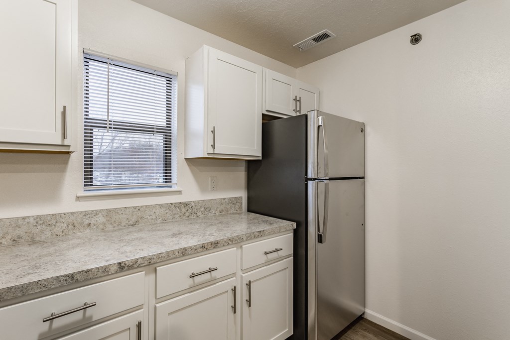 A kitchen with a black refrigerator and white cabinets at Huntington Cove Apartments, Merrillville, IN, 46410