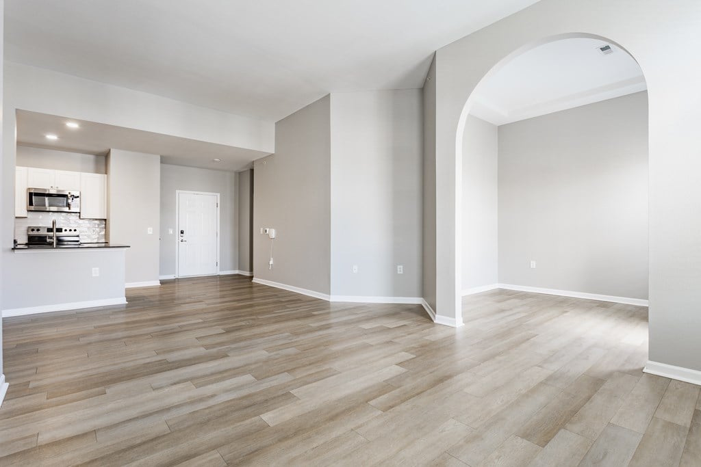 A spacious room with wooden flooring and a large archway.