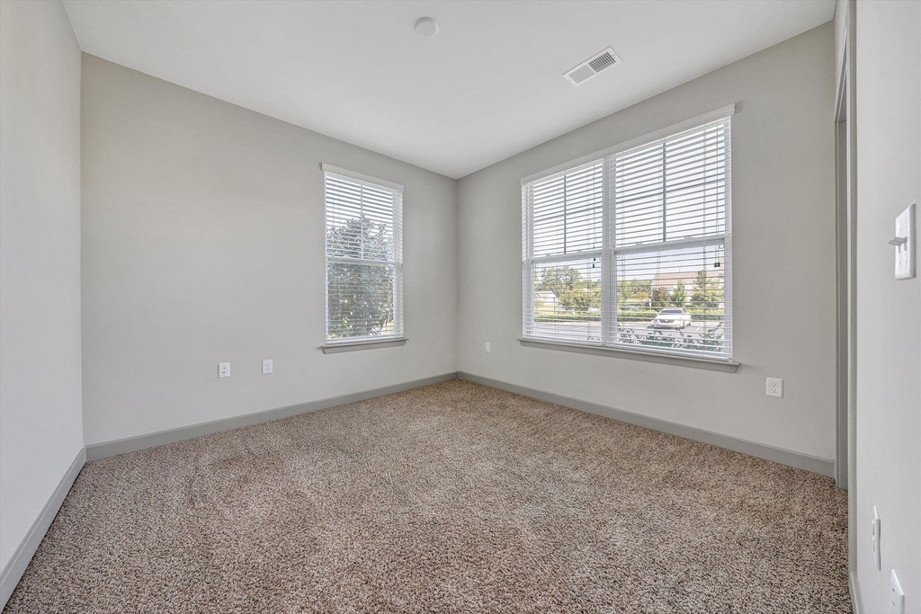 an empty living room with two windows and carpeting  at Avellan Springs Apartments, North Carolina
