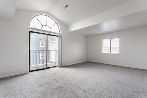 A spacious room with a large arched window and a sliding glass door leading to a balcony at Huntington Cove Apartments, Merrillville, IN, 46410
