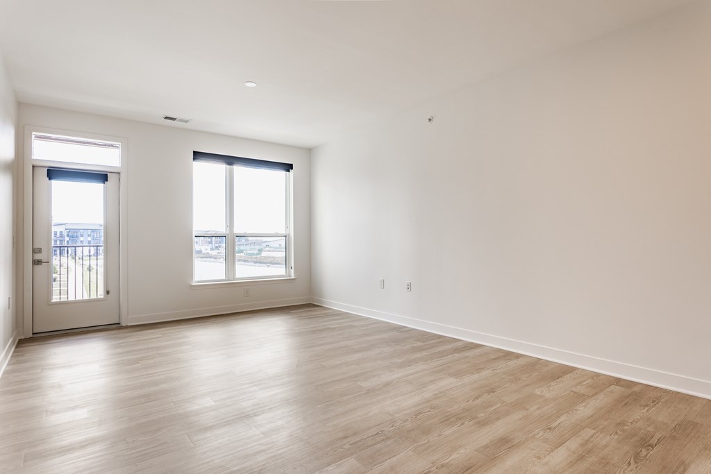 A large empty room with wooden floors and two windows at Upper Vue Flats, Dublin