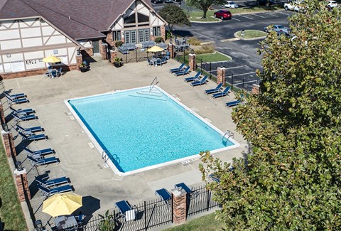 a swimming pool in front of a house with chairs around it at The Timbers Apartments, Evansville, IN, 47715