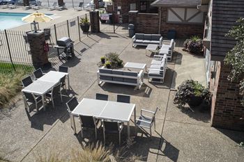 an outdoor patio with tables and chairs and a pool at The Timbers Apartments, Evansville