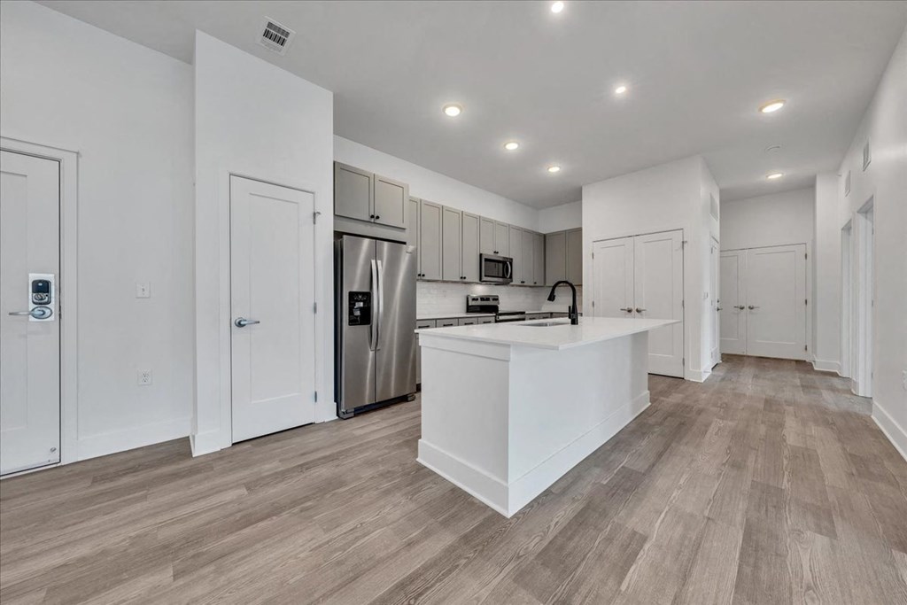a white kitchen with a large island and a stainless steel refrigerator at Luxe 360 in Midlothian, Midlothian