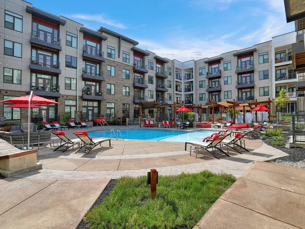 a swimming pool with chaise lounge chairs and umbrellas in front of an apartment building  at Avant & Avant II, Carmel, 46032
