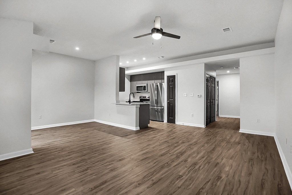 an empty living room with a kitchen and a ceiling fan at Latitudes Apartments, Indiana, 46237