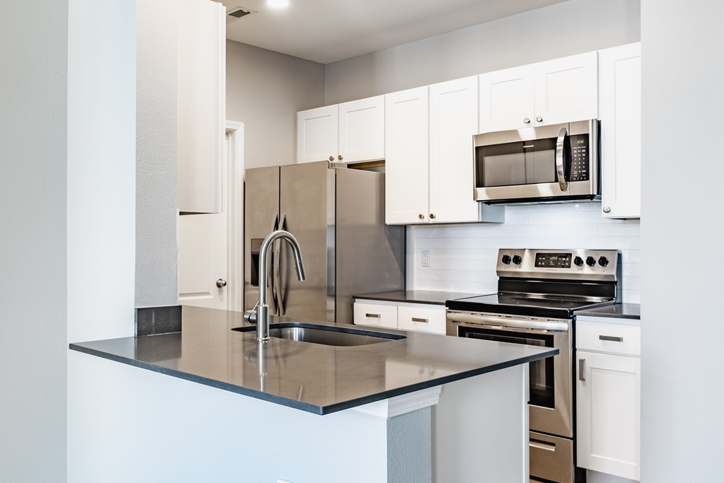 A kitchen with a sink, stove, and refrigerator.