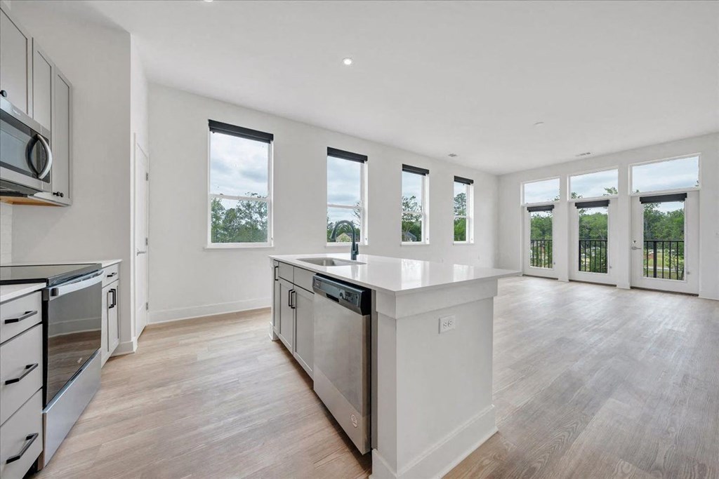 a kitchen and living room with white walls and windows and wood floors at Luxe 360 on Centerpointe Apartments, Midlothian, VA, 23114