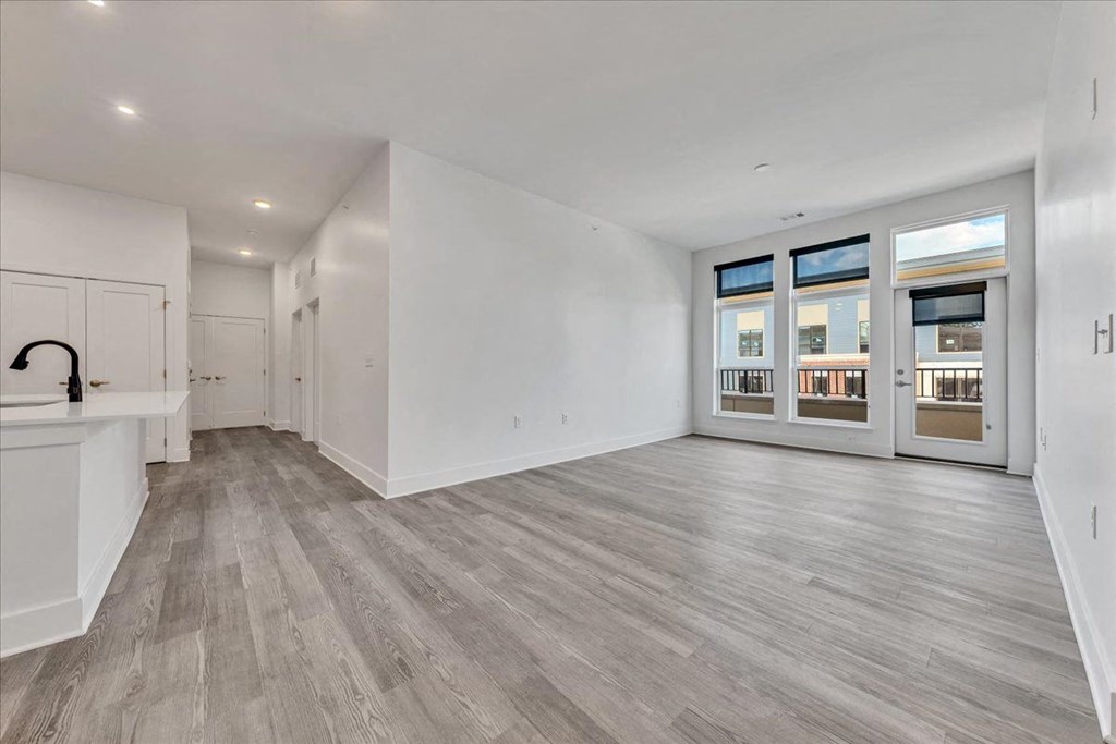 the living room and kitchen of a new home with white walls and wood floors at Luxe 360 in Midlothian, Midlothian, 23114