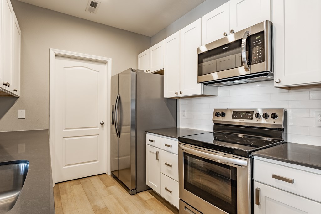 A kitchen with a stove, oven, refrigerator, and microwave.
