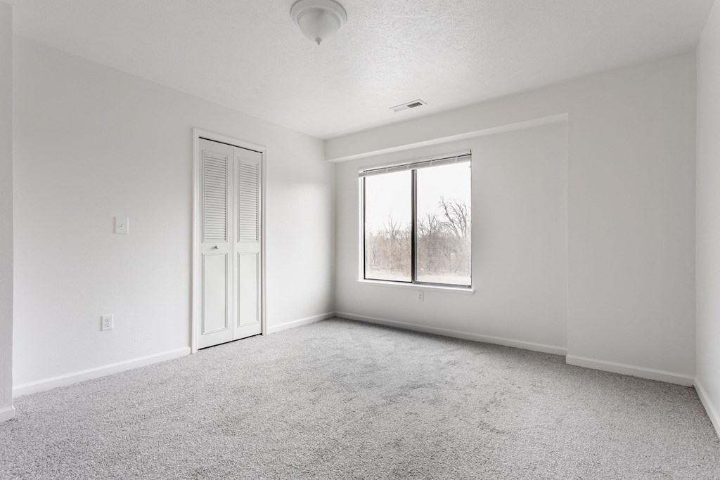 A white room with a carpeted floor, a door, and a window at Huntington Cove Apartments, Merrillville, IN, 46410