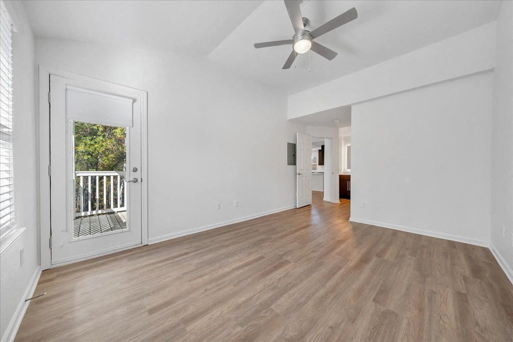 an empty living room with a ceiling fan and a door to a balcony at The Vinings Apartments, Virginia, 23234