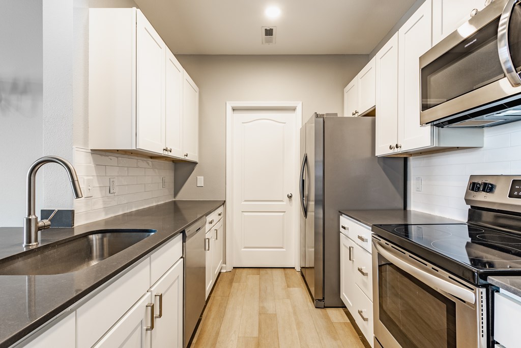 A kitchen with white cabinets and stainless steel appliances.