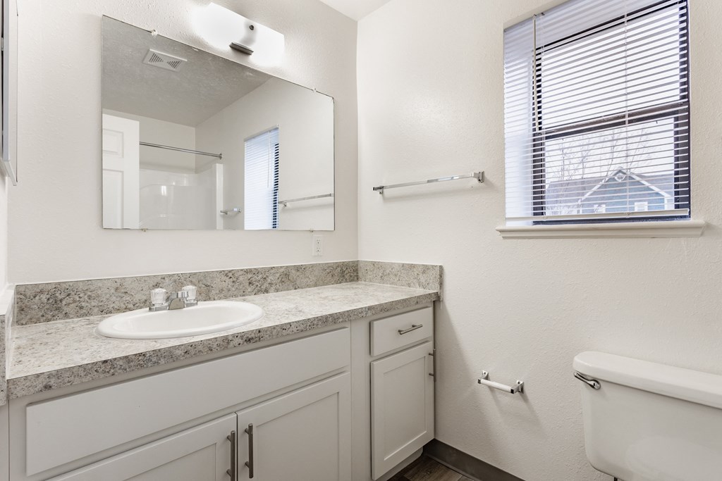 A white bathroom with a sink, mirror, and tub at Huntington Cove Apartments, Merrillville, IN, 46410