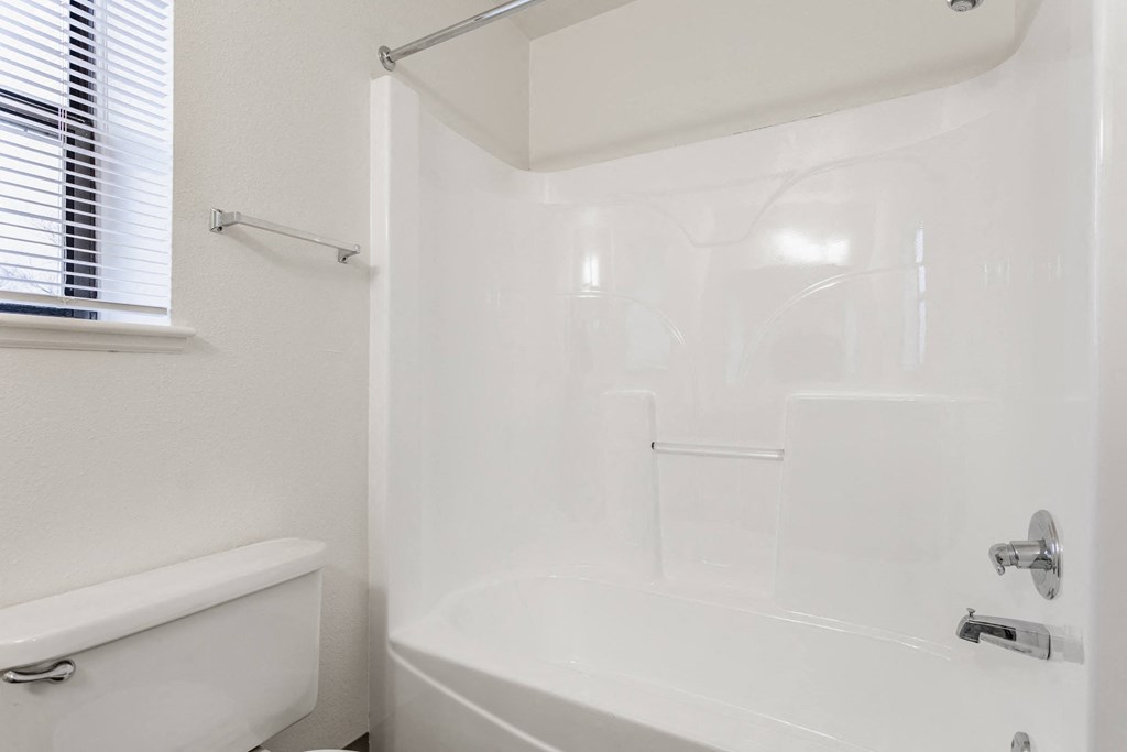 A white bathroom with a tub, shower, and toilet at Huntington Cove Apartments, Merrillville, IN, 46410
