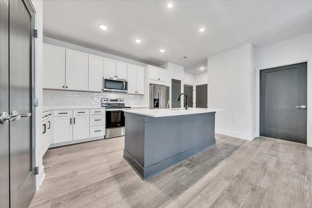 a white kitchen with a blue island in the middle at Luxe 360 in Midlothian, Virginia