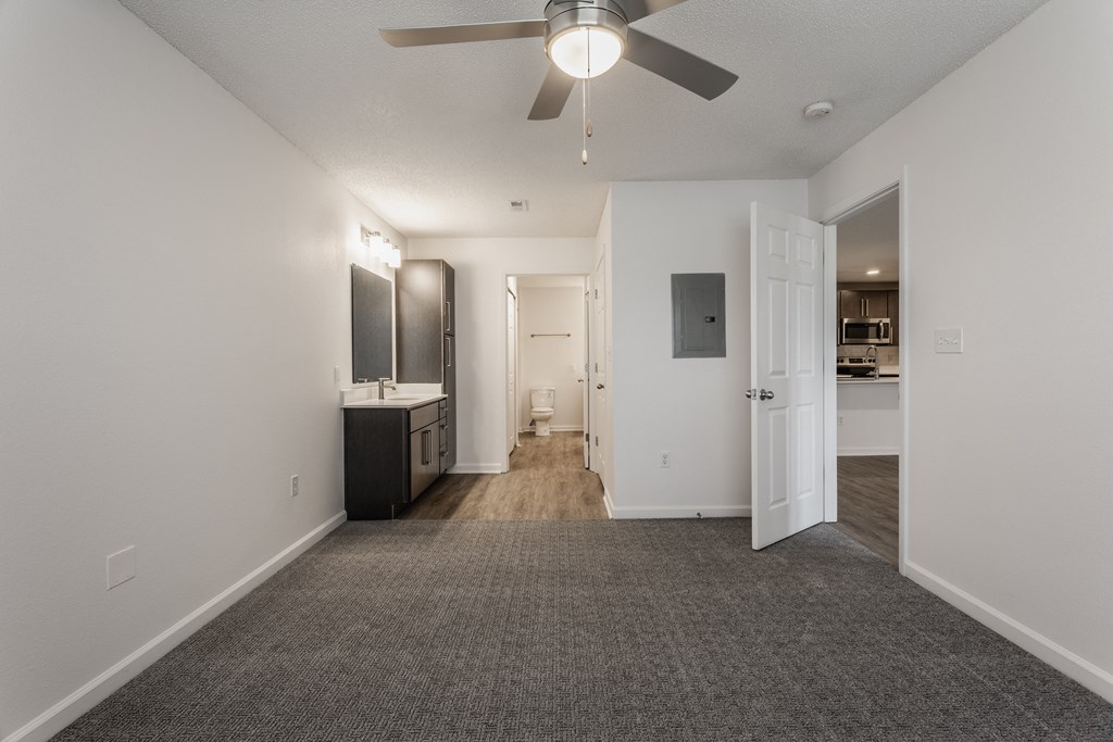 an empty living room with a ceiling fan and a kitchen at Latitudes Apartments, Indianapolis, 46237