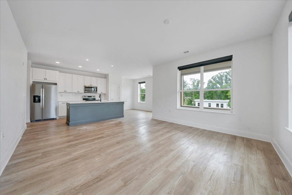 an empty living room with a large window and a kitchen in the background at Luxe 360 in Midlothian, Midlothian